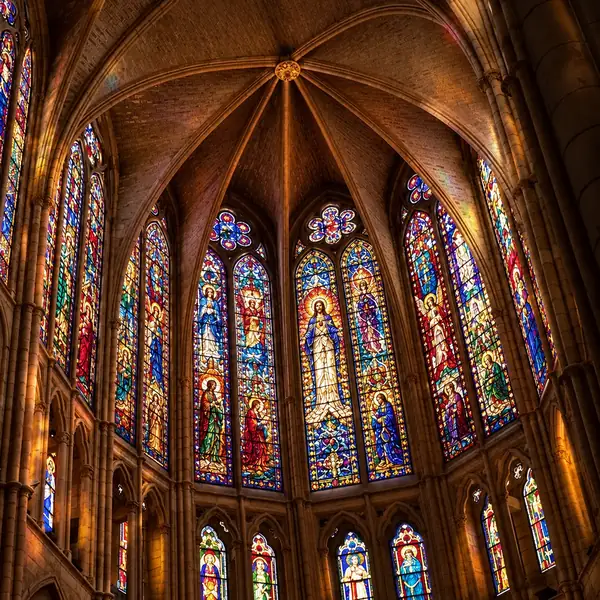 A Gothic cathedral interior with vaulted stonework and colorful stained-glass windows.